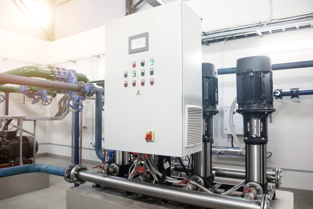 Industry interior of water pump, valves, pressure gauges, motors inside engine room. Urban modern powerful pipelines. Automatic control systems, Industrial pumps in an technical room. Copy text space